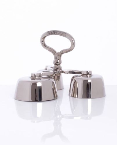 Sklep liturgiczny: Potrójne dzwonki mszalne z mosiądzu niklowanego o srebrnym połysku, z centralnym uchwytem, na białym tle.