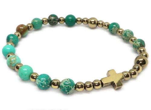 Naturalna bransoletka różańcowa z turkusowego jaspisu cesarskiego i złotych hematytowych koralików, ozdobiona złotym krzyżykiem, ułożona w okrąg na białym tle.
