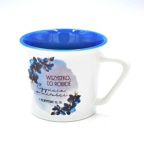 Biały kubek z niebieskim wnętrzem i artystyczną grafiką niebieskich orchidei. Na kubku znajduje się cytat z 1 Kor 16,14: "Wszystko, co robicie, w miłości czyńcie".