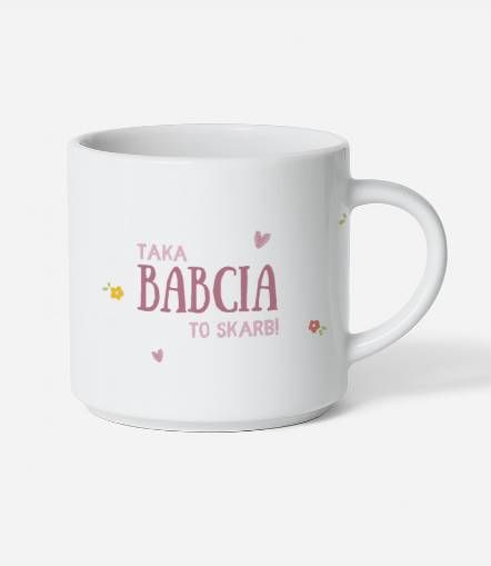 Biały kubek ceramiczny z różowym napisem Taka Babcia to skarb w otoczeniu kwiatów i serc.