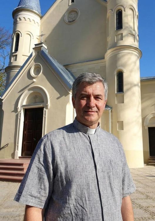 Kapłan przed kościołem ubrany w szara koszulę kapłańską z lnu z krótkim rękawem, naturalny splot materiału  koszule kapłańskie - ceny producenta