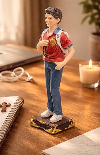 Figurka św. Carlo Acutisa na drewnianym biurku, laptop, słuchawki, świeca, notes z drewnianym krzyżem — aranżacja pokoju młodzieżowego