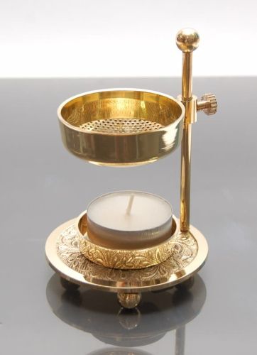 Złota kadzielnica domowa z regulowanym rusztem nad świeczką typu tealight, zdobiona podstawa