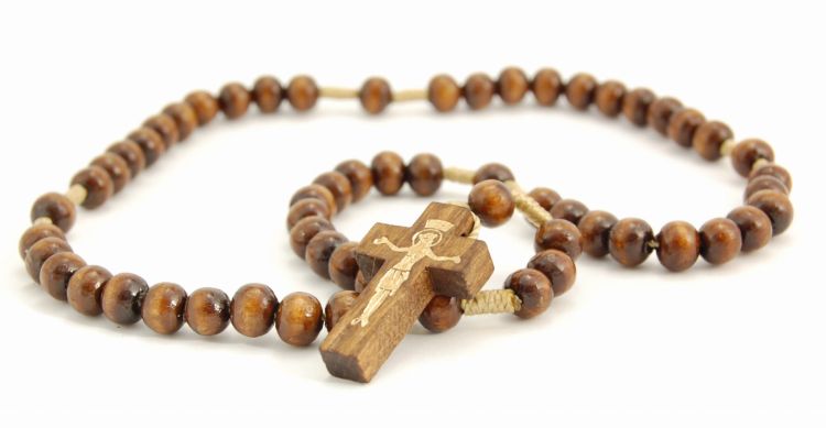 Zdjęcie brązowego różańca drewnianego na sznurku. Koraliki są okrągłe, a krzyżyk prosty, z widoczną pasyjką. Produkt leży na białym tle.